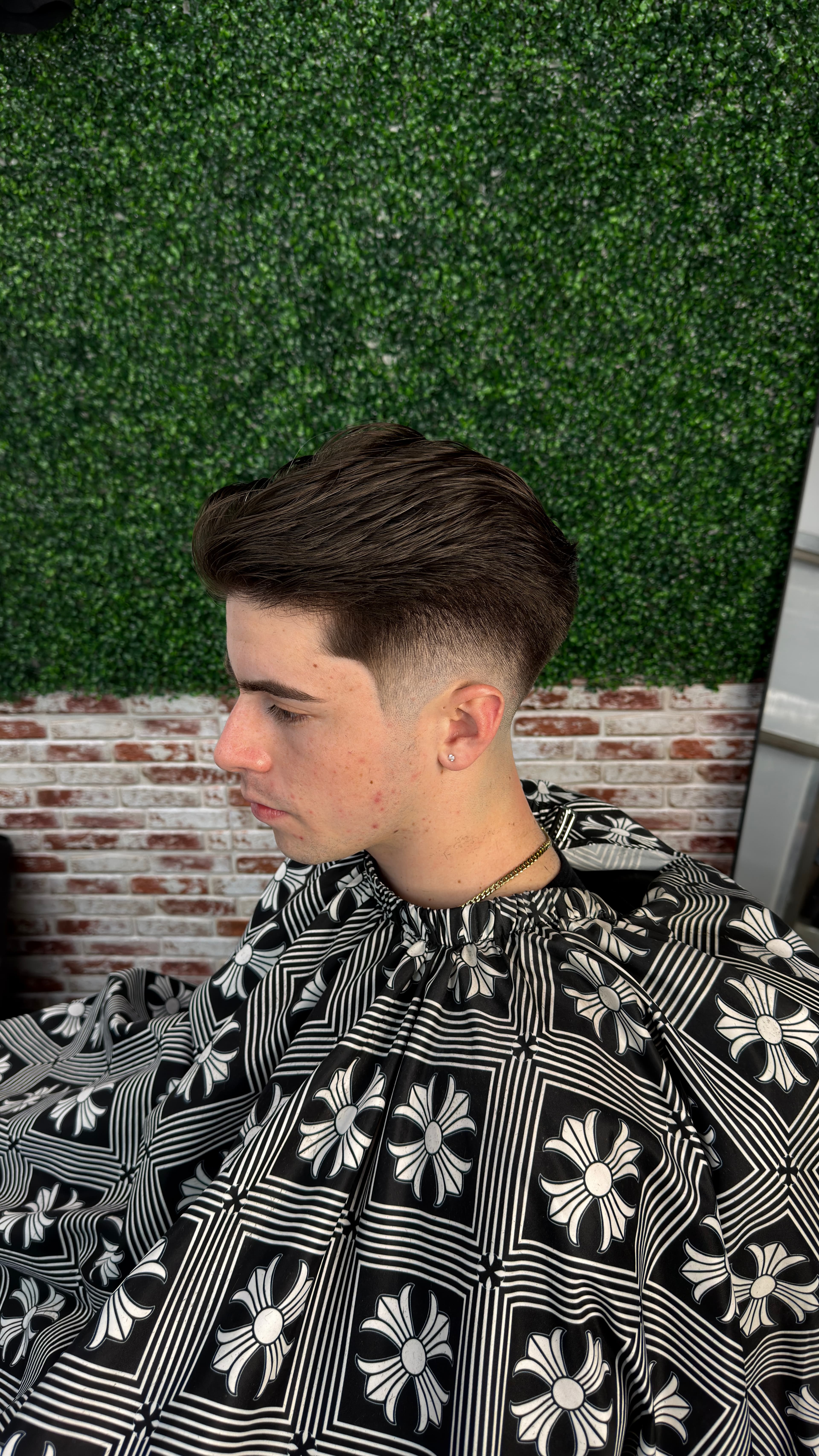 Side view of a swept-back haircut with a close fade around the ear.