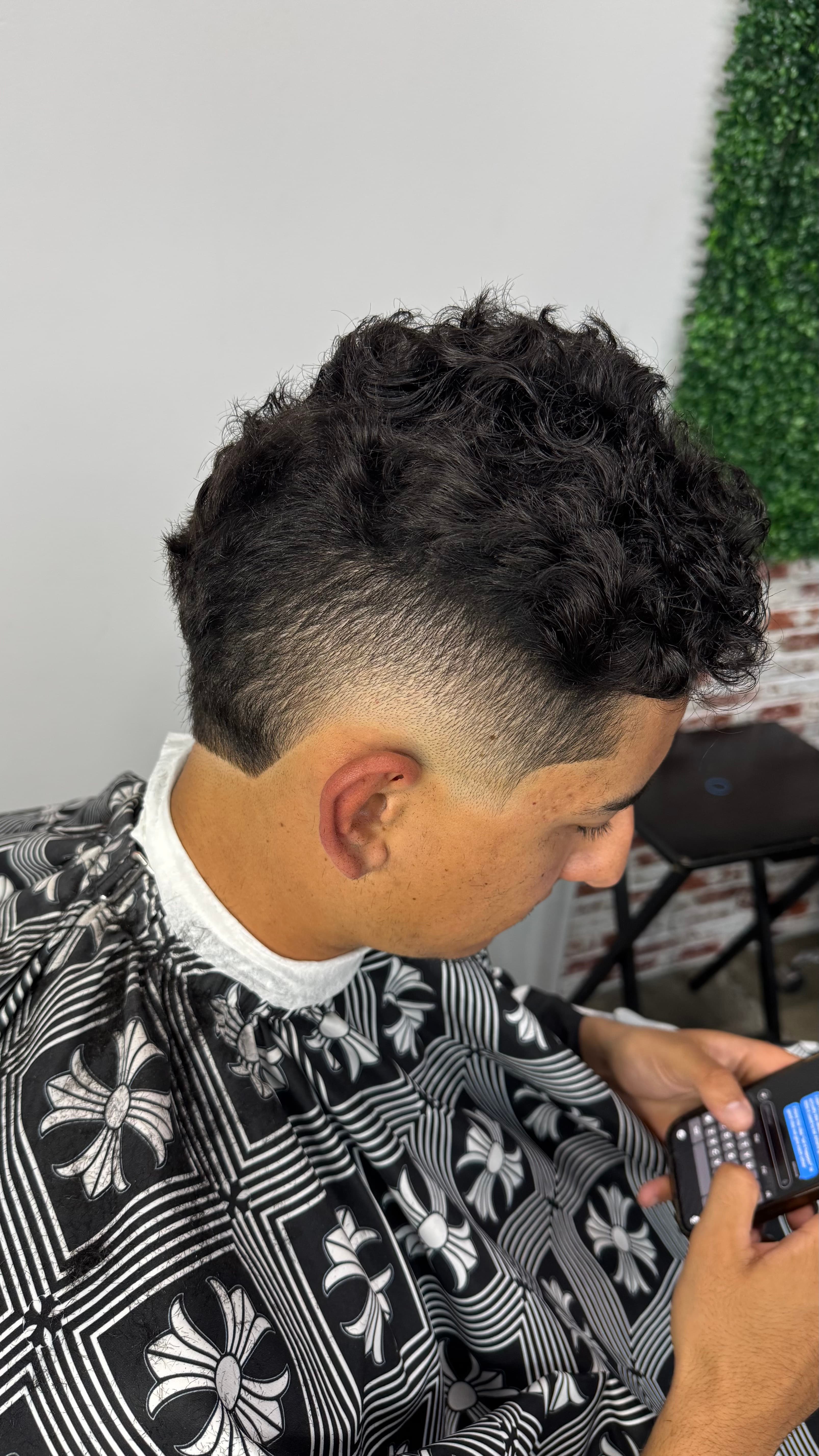 Curly top with tapered sides and a sharply outlined temple and nape.
